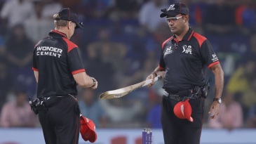 Umpires check players’ bat size on the field during Sunday double-header